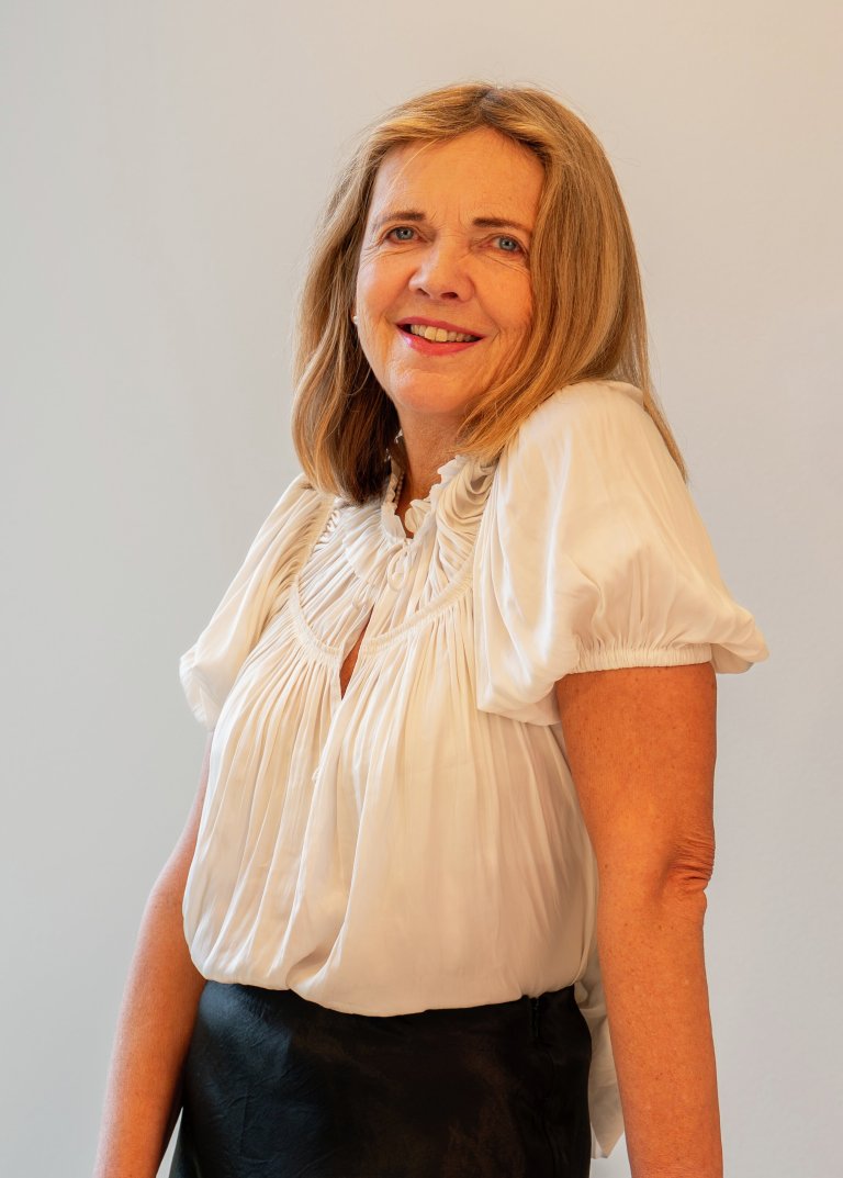 Kvinne i hvit bluse står i møterom.