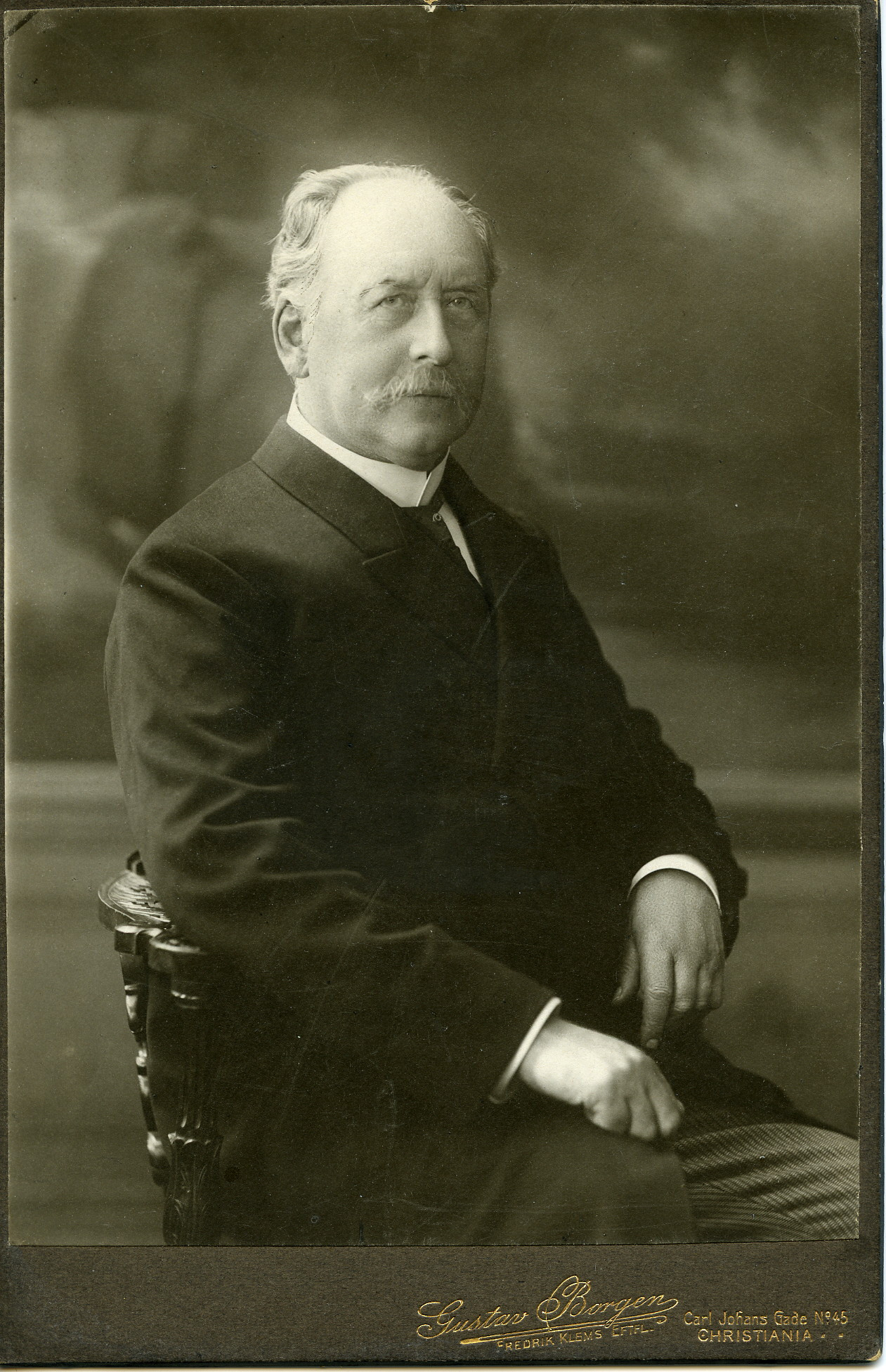 Svart hvitt portrettfoto av Ebbe Hertzberg som sitter på en stol.